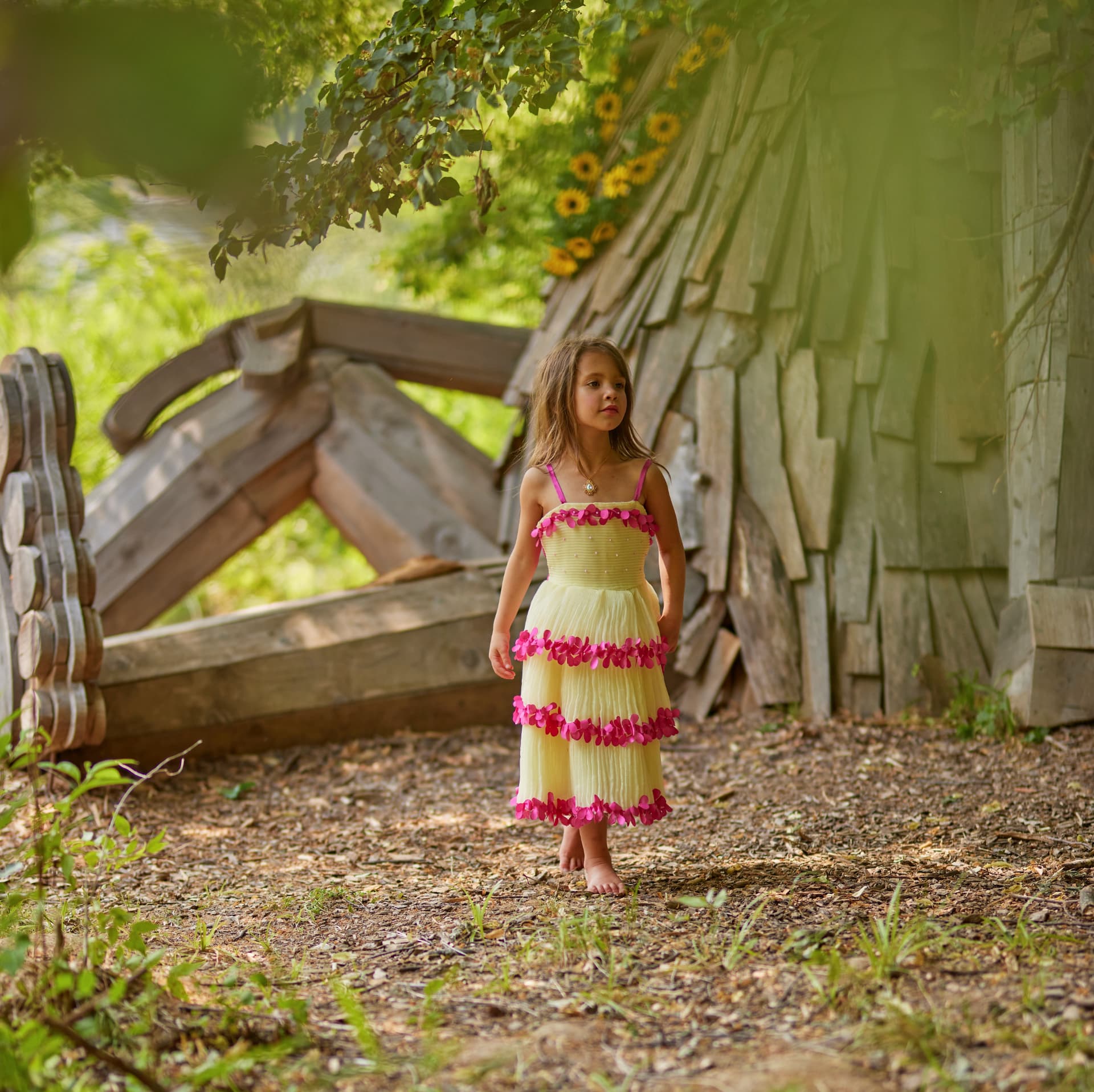 Young girl in a yellow floral dress beside a rustic wooden barn in Central Illinois